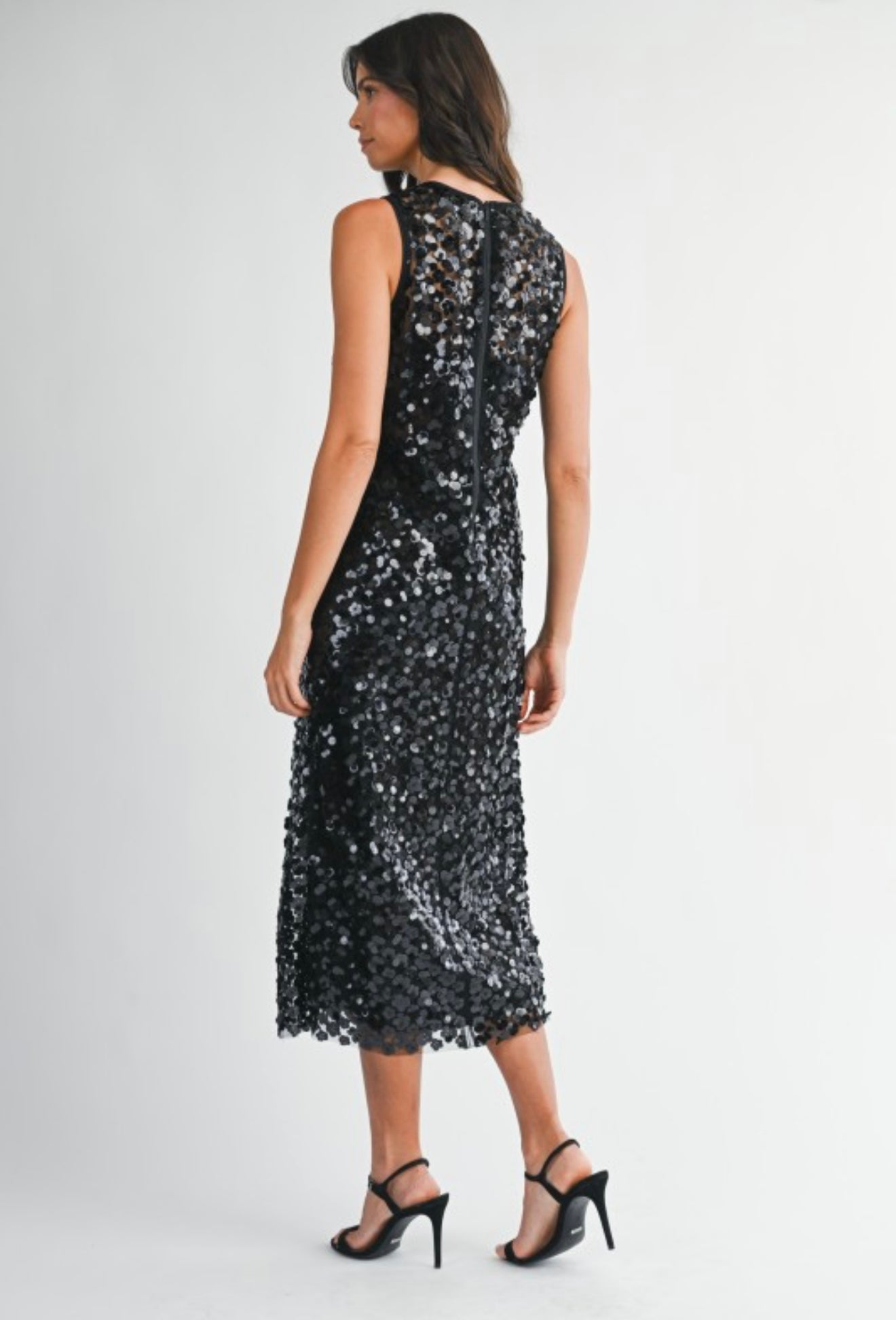 Elegant black sequin dress, sleeveless design, perfect for evening events, paired with black strappy heels.