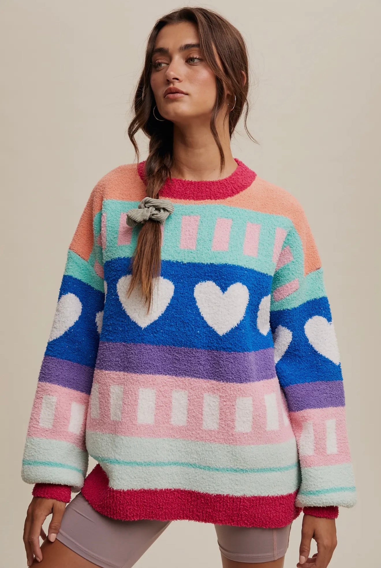 Colorful plush sweater with hearts and stripes, featuring pink, blue, and mint green colors. Ideal for casual wear.