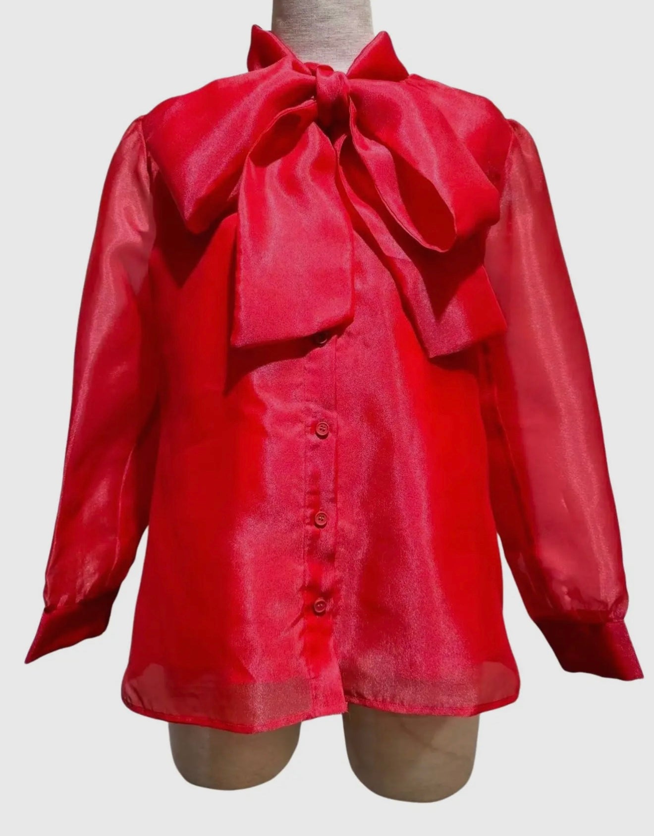 Red silk blouse with bow tie collar and sheer long sleeves for a stylish look.