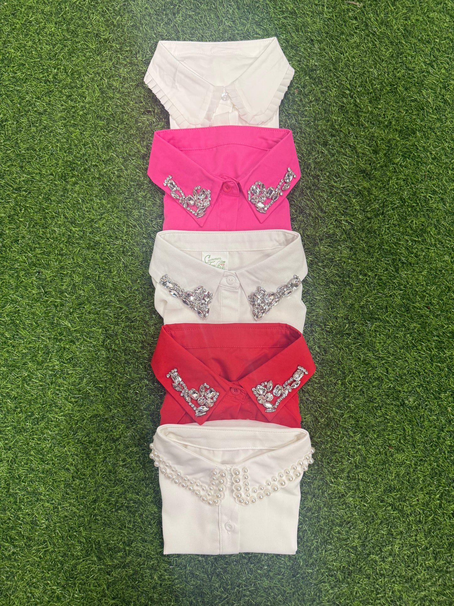 Colorful collared shirts in white, pink, and red with embellished detailing and pearl accents.