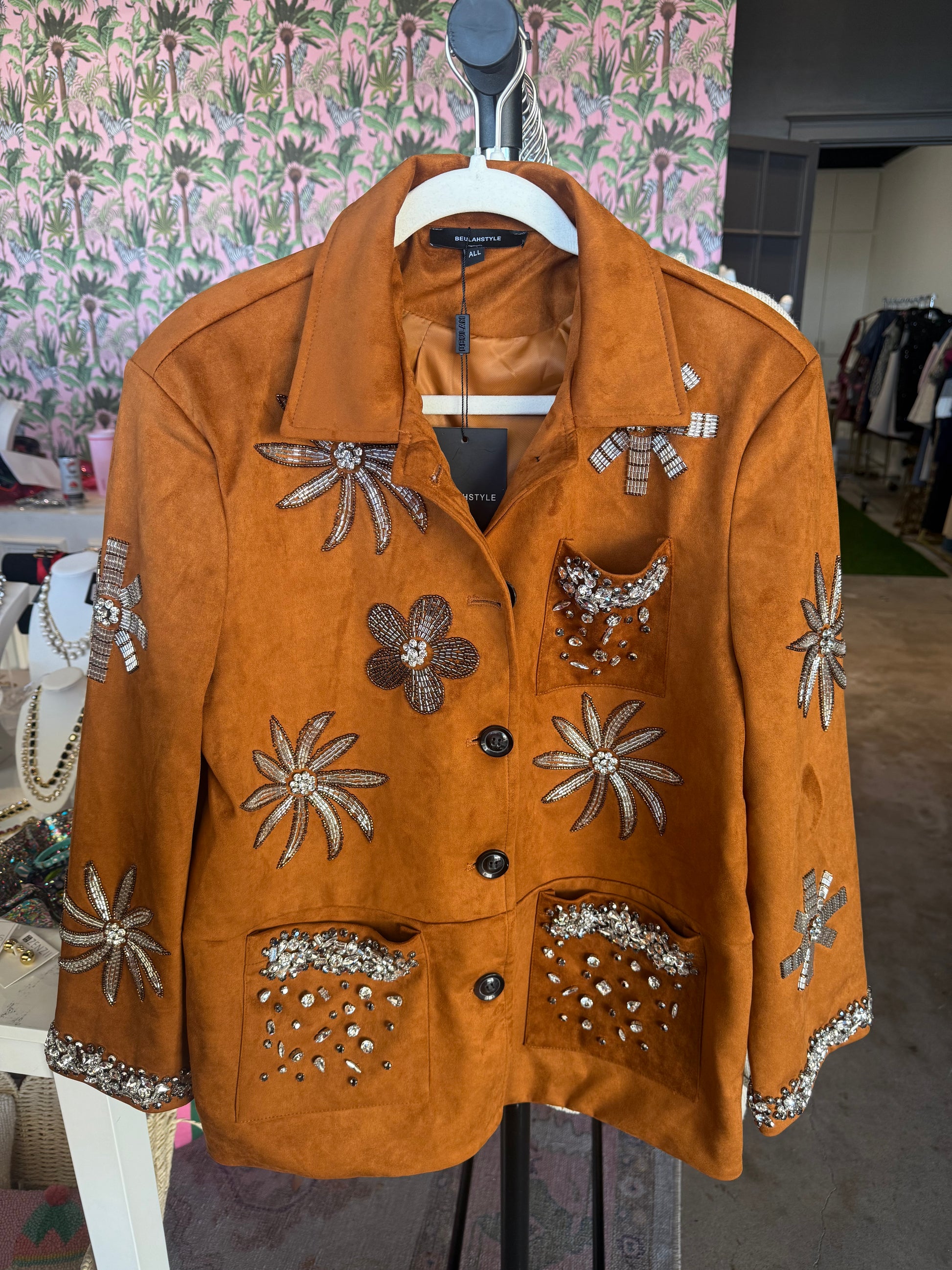 Vintage-style orange suede jacket with floral embellishments and rhinestones, featuring two front pockets.