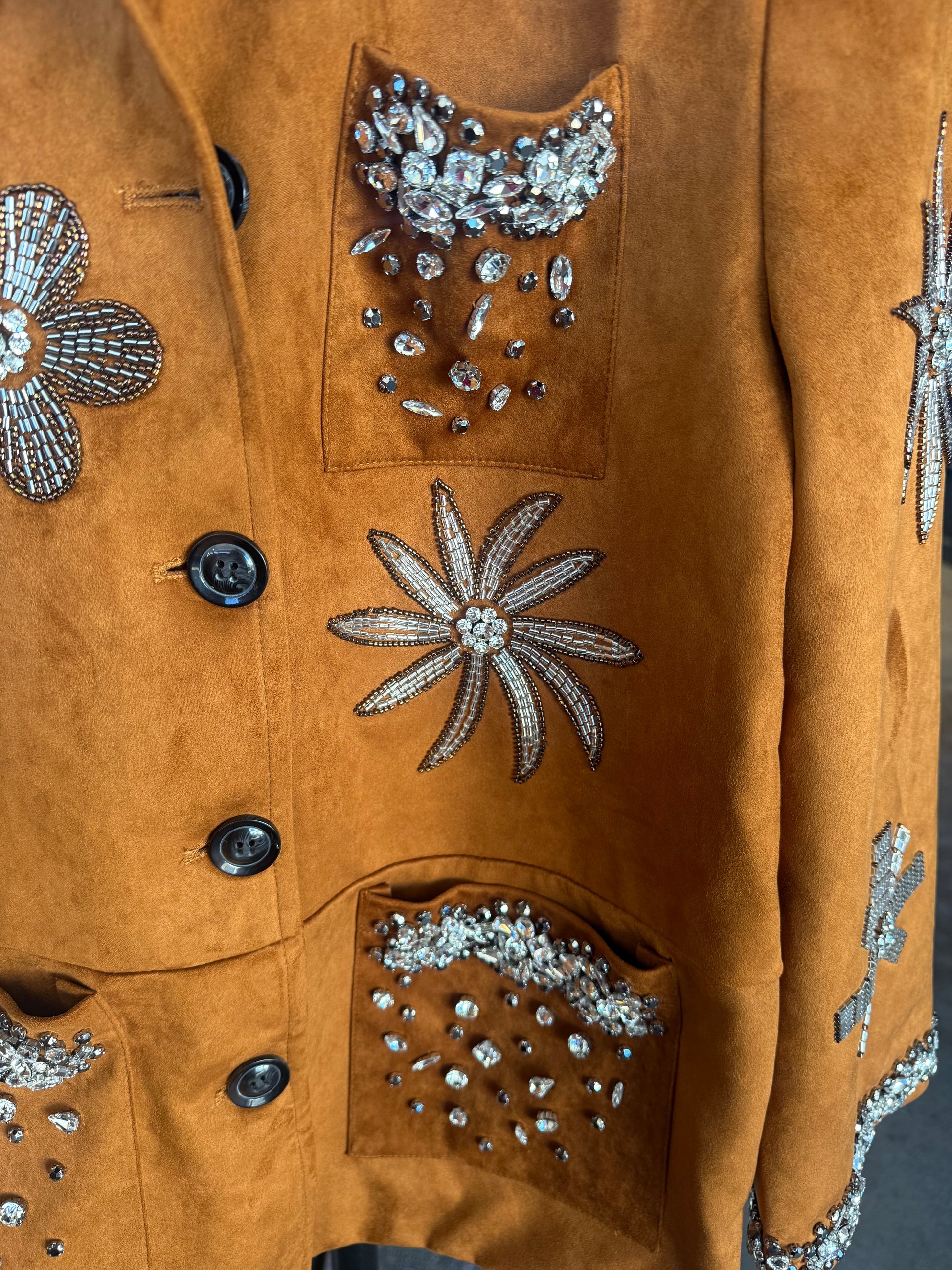 Stylish brown suede jacket with intricate crystal embellishments and floral designs.